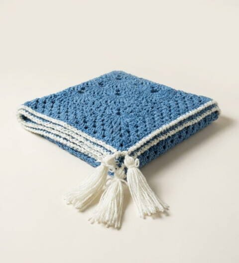 Handmade blue crochet shawl with white tassel tie detail and fan-pattern stitching by ShapersBliss